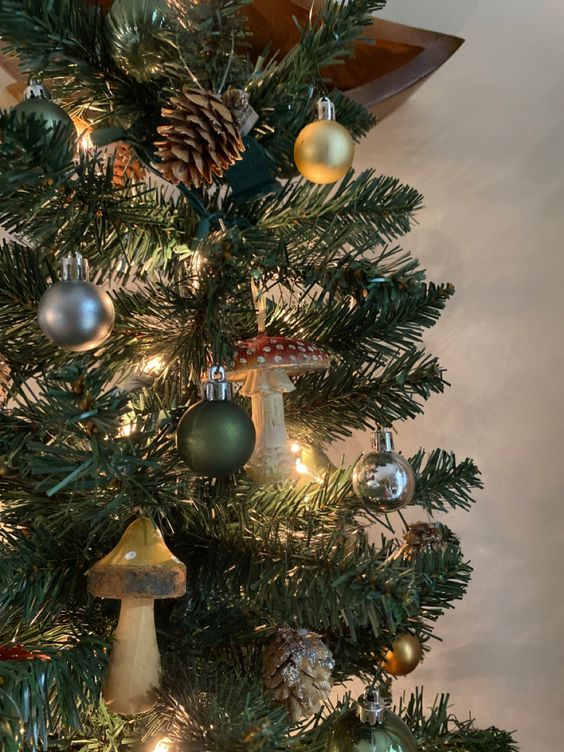 a Christmas tree with lights, mushrooms, ornaments and pinecones is a lovely idea for a woodland Christmas space