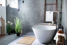 a beautiful contemporary bathroom with concrete walls and a floor, a shower space, an oval tub, a ladder and a bench plus potted plants