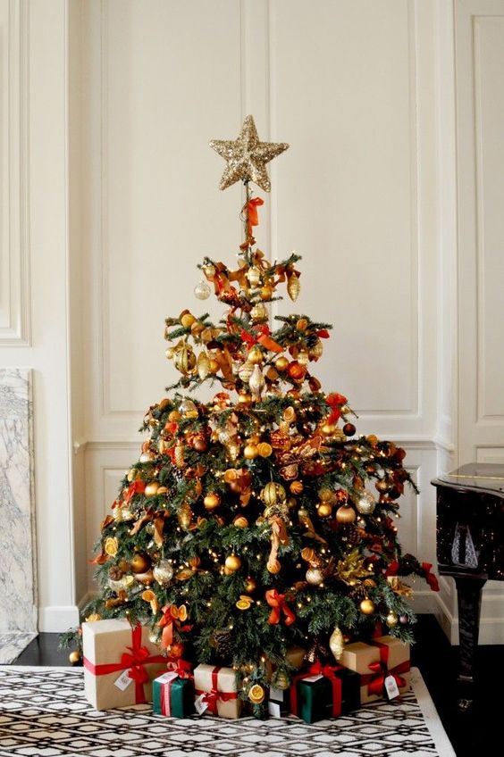 a beautiful vintage Christmas tree decorated with yellow, rust, ornage and brown ornaments, citrus slices and red bows plus lights