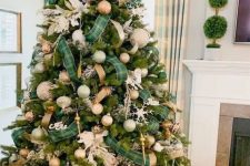 a bold Christmas tree decorated with metallic, emerald and copper ornaments, gold and green plaid ribbons and snowflakes plus snowy branches on top
