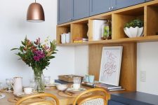 a bold blue kitchen with shaker cabinets, open stained shelves and a matching table and chairs plus a copper pendant lamp