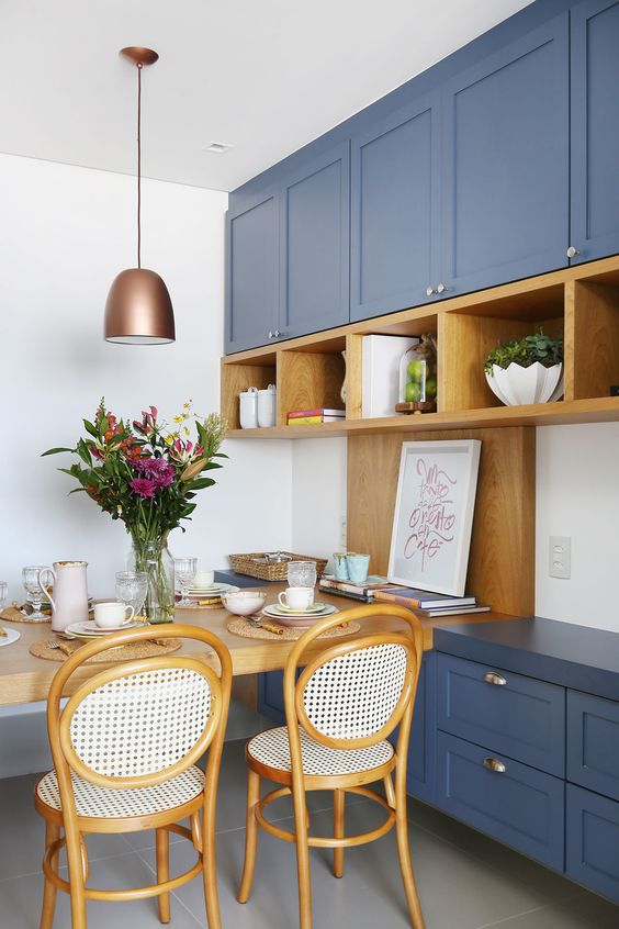 a bold blue kitchen with shaker cabinets, open stained shelves and a matching table and chairs plus a copper pendant lamp