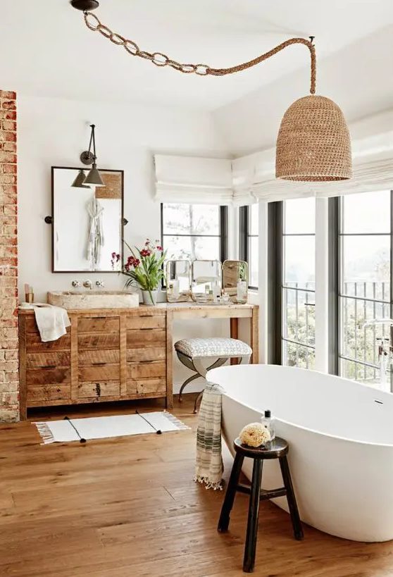 a catchy bathroom with a glazed wall, a reclaimed wood vanity and a pendant lamp, hardwood flooring and an oval bathtub