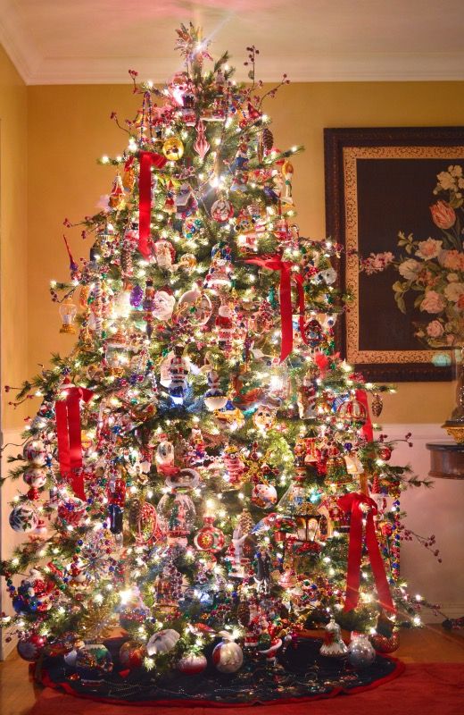 a colorful vintage-inspired Christmas tree decorated with lights, red ribbons, berry branches, colorful ornaments and lots of other stuff