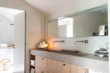 a contemporary bathroom with a concrete and wood built-in vanity, a long mirror, a chic tiled floor is very welcoming