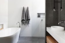 a contemporary bathroom with a concrete tile floor and some walls, a white oval tub, a built-in vanity and niches for storage