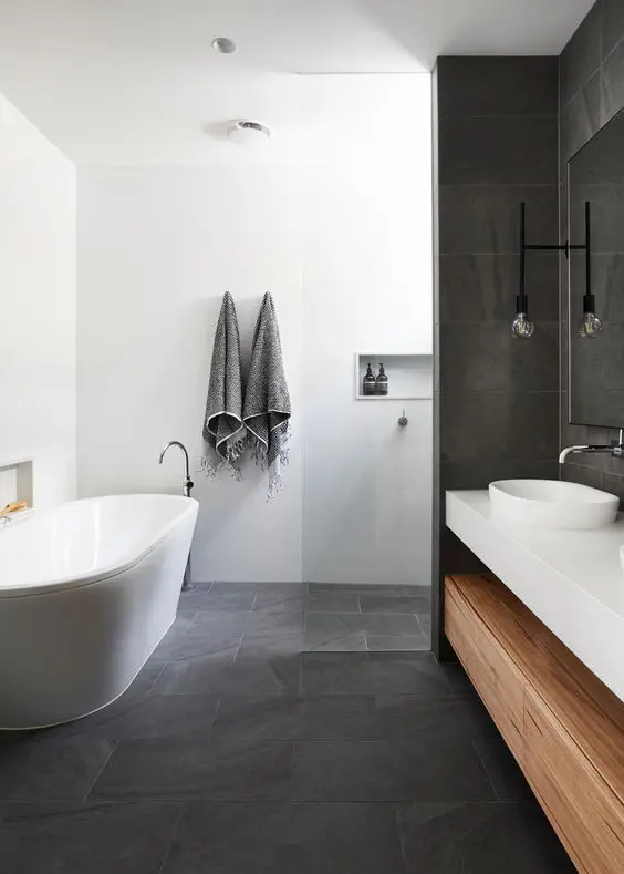 a contemporary bathroom with a concrete tile floor and some walls, a white oval tub, a built in vanity and niches for storage