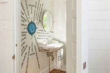 a creative nautical under stair powder room with a cool artwork right on the wall, a free-standing sink and a window