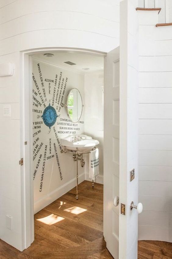a creative nautical under stair powder room with a cool artwork right on the wall, a free standing sink and a window