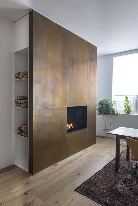 a dining space with an accent feature   a fireplace clad with aged metal sheets and with hidden firewood storage