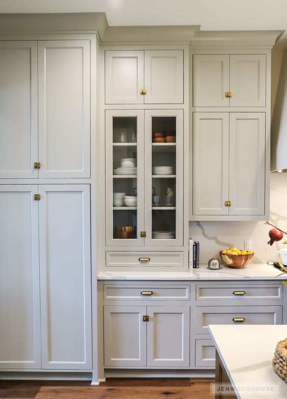 a dove grey shaker style kitchen with matching in color crown molding that connects the upper cabinetry with the ceiling is amazing