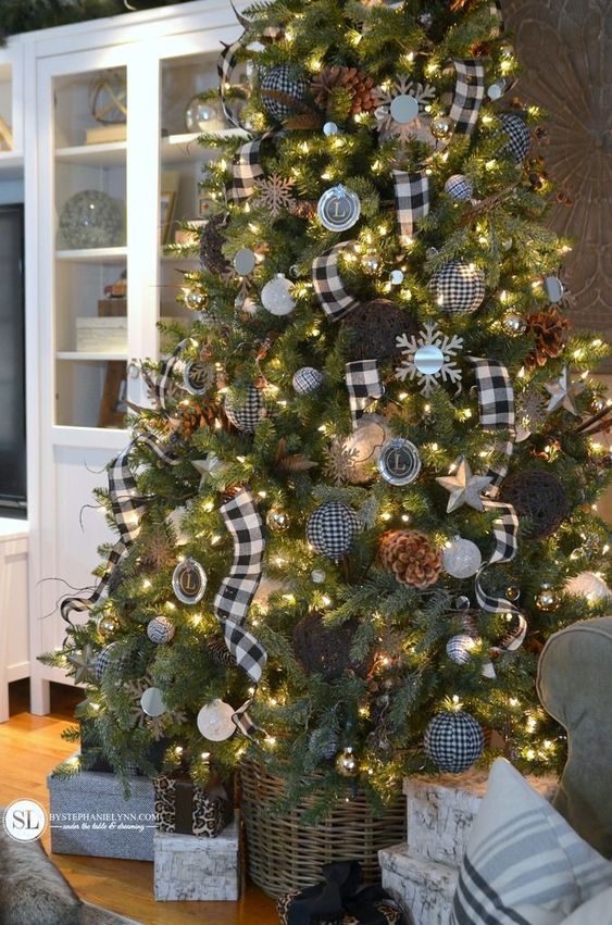 a farmhouse Christmas tree with plaid and black and white ornaments, buffalo check ribbons, lights, pinecones and chalkboard monograms