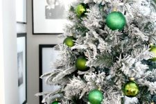a flocked Christmas tree decorated with green ornaments of various shades looks glam, chic and bold and feels pretty natural at the same time