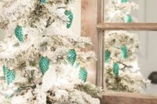 a flocked Christmas tree decorated with white semi sheer ribbon and green pinecone ornaments is a chic idea to go for