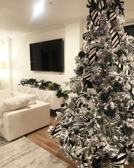 a flocked Christmas tree with black, white and silver ornaments, lights, striped ribbons and checked baubles is amazing
