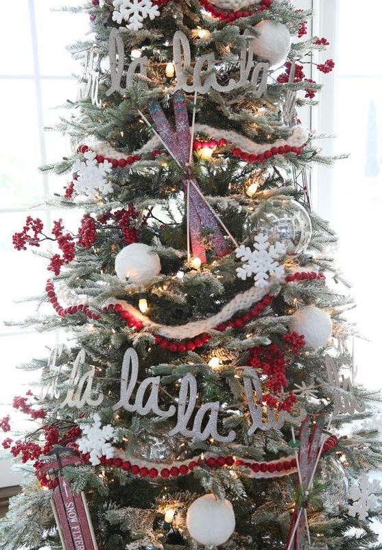 a flocked Christmas tree with lights, cranberry garlands, letters, skis and sleighs is a chic vintage-inspired idea