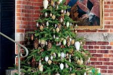 a forest Christmas tree with gold, white and silver pinecone ornaments, real pinecones, lights and vines is amazing