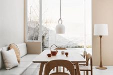 a fresh and serene dining space with a light green banquette seating, a wooden table and chairs plus a white pendant lamp