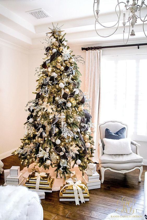 a glam Christmas tree decorated with white and gold ornaments, with black ribbon with white rims and white fabric blooms