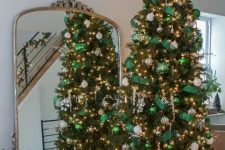 a gorgeous Christmas tree styled with emerald ornaments and ribbons, white and silver ornaments, lights and large snowflakes looks wow