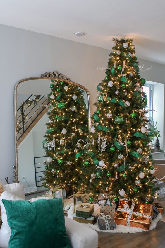 a gorgeous Christmas tree styled with emerald ornaments and ribbons, white and silver ornaments, lights and large snowflakes looks wow