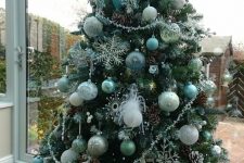 a green Christmas tree with white, mint and green ornaments, snowflakes and beads, pinecones and icicles is cool