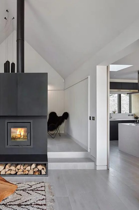 a hearth clad with black metal with firewood storage is a gorgeous way to cozy up your Scandinavian space