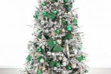 a jaw-dropping flocked Christmas tree styled with emerald ribbons and ornaments, gold and silver ornaments and beads and a silver star tree topper