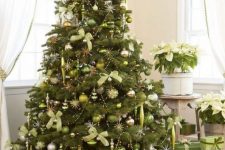 a large Christmas tree decorated with light green and silver ornaments, silver beads and light green bows plsu green gift boxes under the tree