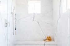 a large shower space clad with white marble and with marble herringbone tiles on the floor is amazing and looks very refined and chic