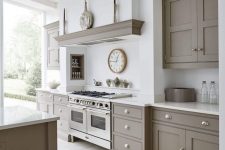 a light-filled grey and white kitchen with shaker-style cabinets, white stone countertops and a backsplash plus a beige tile floor