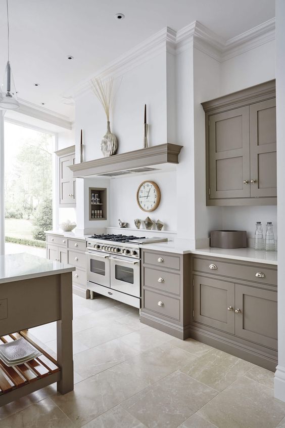 a light-filled grey and white kitchen with shaker-style cabinets, white stone countertops and a backsplash plus a beige tile floor
