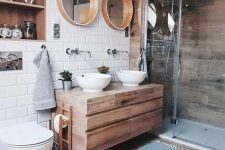 a lovely contemporary bathroom with a wood clad shower space, a wooden vanity, mirrors in wooden frames, a hardwood floor, a niche clad with wood