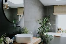 a lovely contemporary bathroom with concrete walls and a floor, a black accent wall, a floating vanity, potted greenery and a round sink