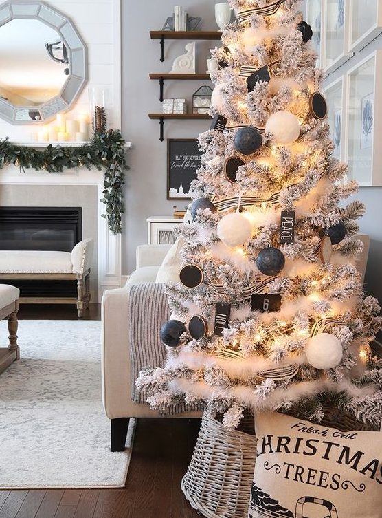 a lovely flocked Christmas tree with lights, black and white ornaments, black wood slice ones, lights and snowy garlands