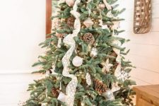 a lovely rustic or woodland Christmas tree with lace ribbons, pinecones, white ornaments, lights and animal-shaped figurines