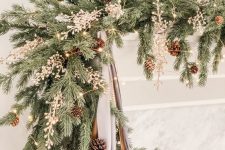 a lush evergreen Christmas garland with pinecones and berries plus lights and mercury glass ornaments is cool for a mantel