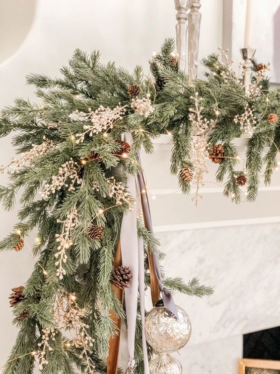 a lush evergreen Christmas garland with pinecones and berries plus lights and mercury glass ornaments is cool for a mantel
