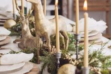 a magical Christmas tablescape with neutral porcelain, tall and thin candles, gilded deer and ornaments plus greenery is amazing