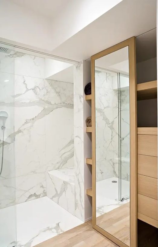 a minimalist bathroom done with white marble in the shower zone and a large sleek closet of wood to store everything
