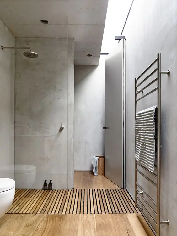 a minimalist bathroom with concrete walls and a hardwood floor for more warmth, a skylight for natural light