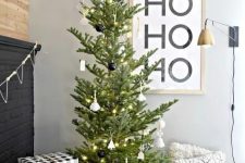 a modern Christmas tree with white and black ornaments and lights is a stylish idea that will fit a Scandinavian space, too
