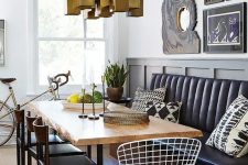 a modern dining area with a black leather banquette and a raw edge dining table, a statement gold geometric chandelier
