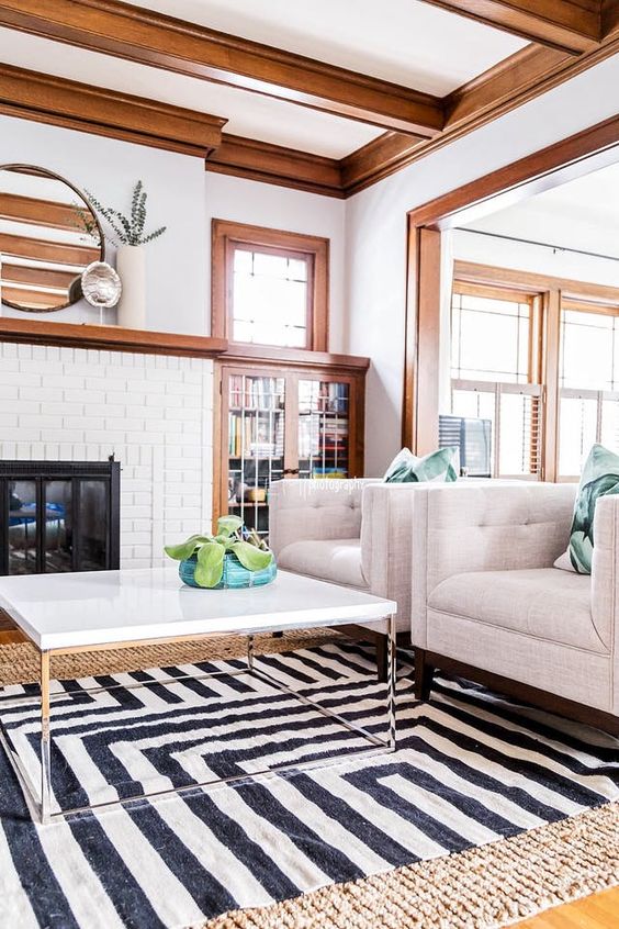 a modern farmhouse living room with a ceiling with stained crown molding and wooden beams, crown molding framing the doors and the mantel matching