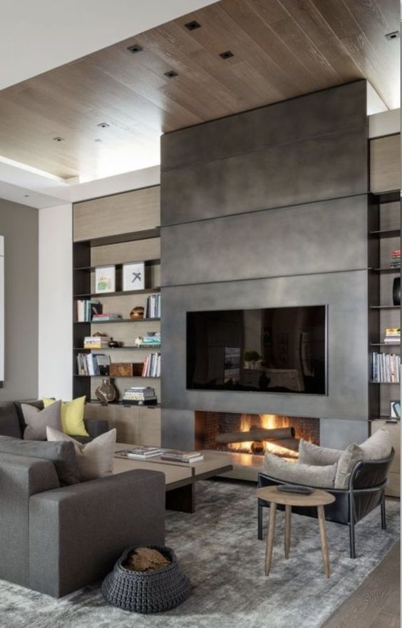 a modern living room done in all shades of grey, with a low coffee table, a fireplace clad with metal and a TV over it