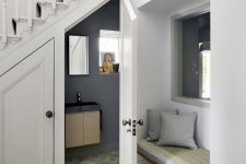 a modern under stair powder room with graphite grey walls, printed tiles, a window with artworks and black appliances