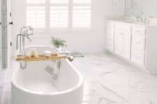 a neutral bathroom with planked wood walls, a white marble tile floor, a catchy bathtub and a large vanity