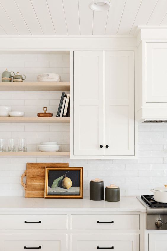 a neutral farmhouse kitchen with shaker style cabinets connected to the ceiling with crown molding, open shelving, black handles for a contrast is wow