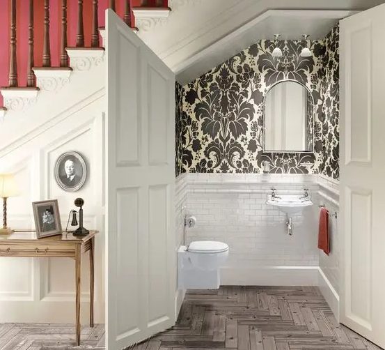 a powder room styled with white tiles and vintage printed wallpaper for an elegant vintage feel