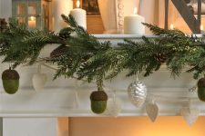 a pretty woodland Christmas mantel with evergreens, pinecone ornaments and real ones, pillar candles and vintage teaware